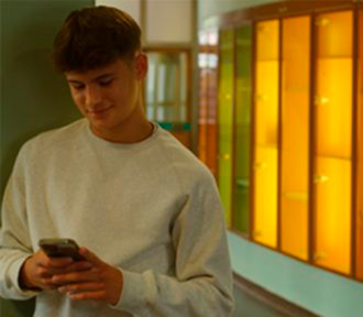 Teenager i hvid sweatshirt kigger på mobil