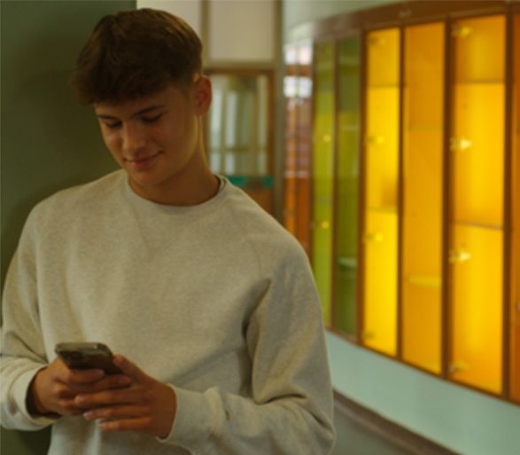 Teenager i hvid sweatshirt kigger på mobil