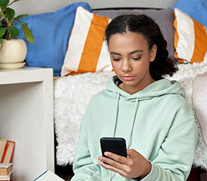 Teenager sider på sit værelse med mobil